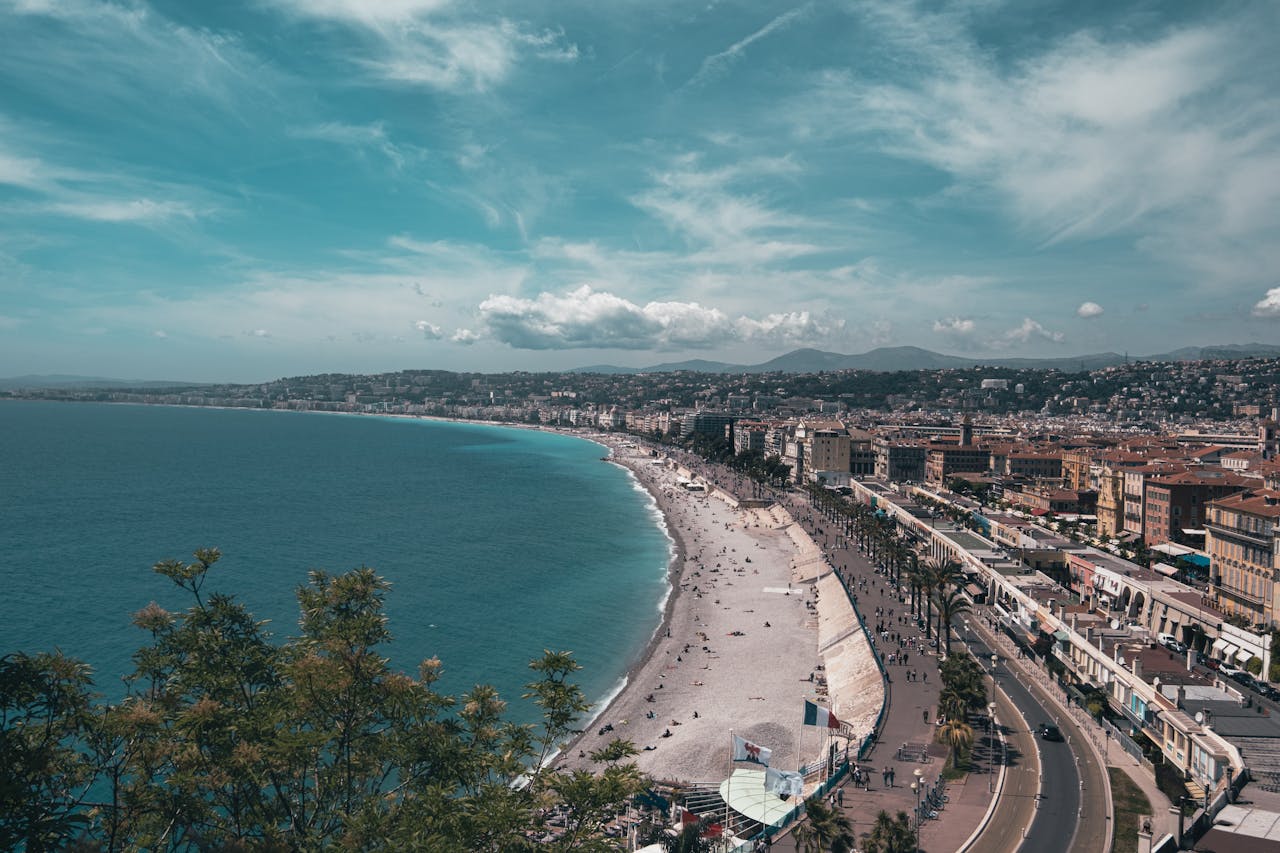 Stunning aerial view of Nice, France with bustling beachfront under a clear summer sky.